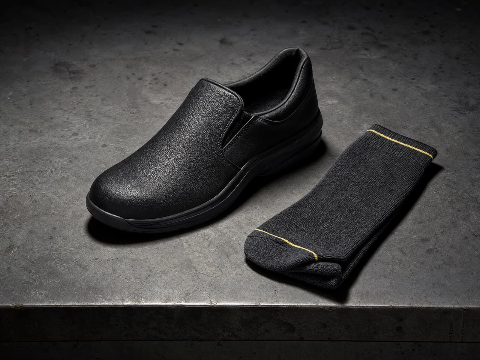 Soft-soled work shoe shown beside an Onshift sock on a workbench